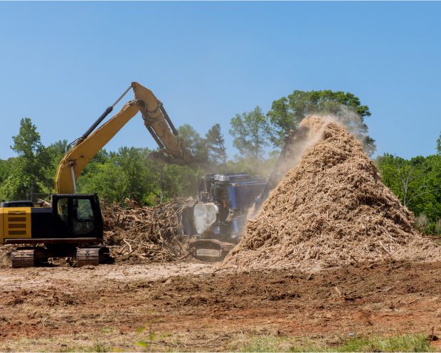 Excavator beside large pile of wood chips.
